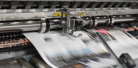 Druckerpresse wirft bedrucktes Papier heraus.