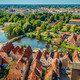 Lübeck (Modul 7) Lübeck aus der Vogelperspektive auf der man Wasser, Haussiedlungen und Wälder sehen kann.