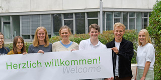 Students stand in front of the GB3 with a cordial welcome banner.