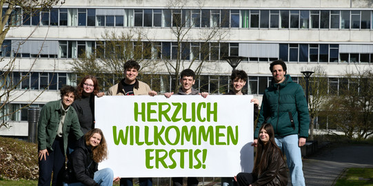 Studierende stehen mit einem Herzlich Willkommen-Banner vor dem GB3.