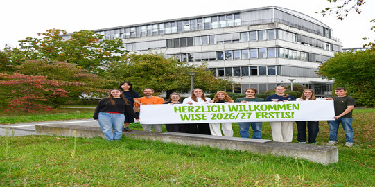 Studierende stehen mit einem Herzlich Willkommen-Banner vor dem GB3.