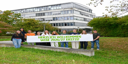 Titelbild Erstis Studierende stehen mit einem Herzlich Willkommen-Banner vor dem GB3.