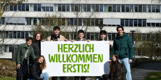 Studierende stehen mit einem Herzlich Willkommen-Banner vor dem GB3.