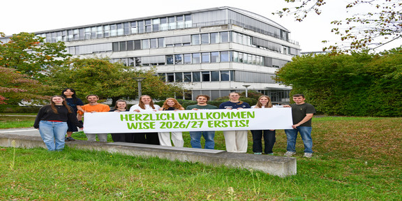 Titelbild Erstis Studierende stehen mit einem Herzlich Willkommen-Banner vor dem GB3.