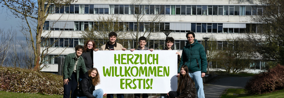 Studierende stehen mit einem Herzlich Willkommen-Banner vor dem GB3.