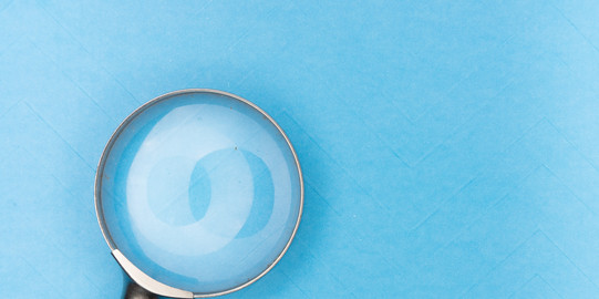 Magnifying glass on light blue background.