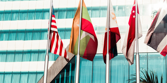 Five flags of countries hang side by side on a pole.