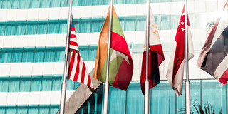 Five flags of countries hang side by side on a pole.