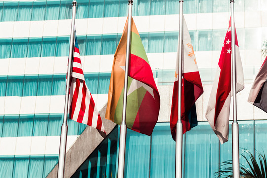 Five flags of countries hang side by side on a pole.