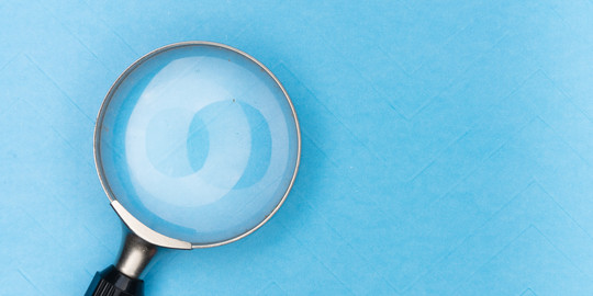 Magnifying glass on light blue background.