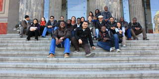 Group picture of the SPRING students sitting on stairs.