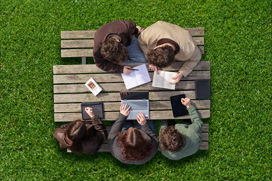 Studierende werden von der Vogelperspektive beim arbeiten draußen an einem Tisch gezeigt.