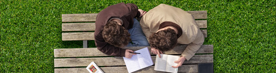 Studierende werden von der Vogelperspektive beim arbeiten draußen an einem Tisch gezeigt.