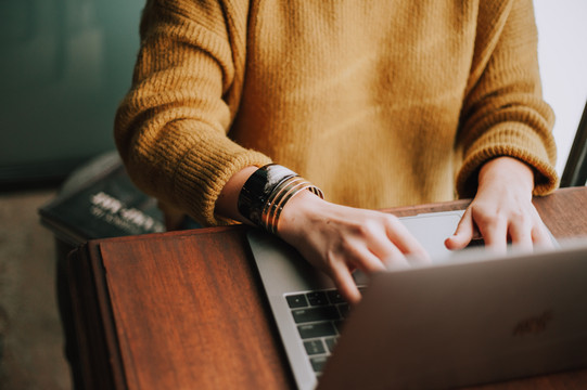 Woman sits at the laptop and types something.