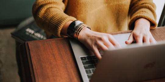 Frau sitzt am Laptop und tippt etwas ein.
