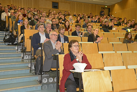 Hörsaal mit Menschen die nach dem Vortrag zusammen klatschen.