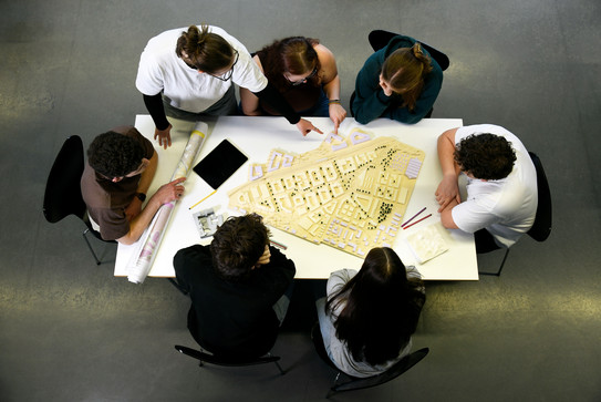 Students sit at a table and work together on a project.