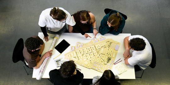 Studierende sitzen an einem Tisch und arbeiten zusammen an einem Projekt.