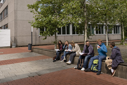 Students sit on a wall and exchange ideas.