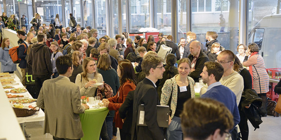 Dortmunder Conference People are at an event and are sitting at round tables and having conversations.