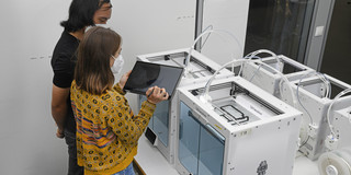 CAD, 3D Modell Studierende stehen vor 3D-Drucker und begutachten den Fortschritt.