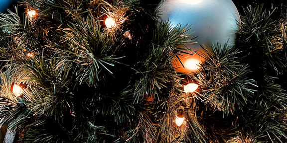 Blaue Weihnachtskugeln hängen an einem Tannenbaum.