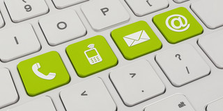 A white keyboard with four green keys. On the green keys are symbols like a telephone, a cell phone, an envelope and an „@“
