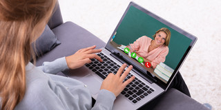 Frau sitzt am Laptop und hält eine Videokonferenz mit einer anderen Frau ab