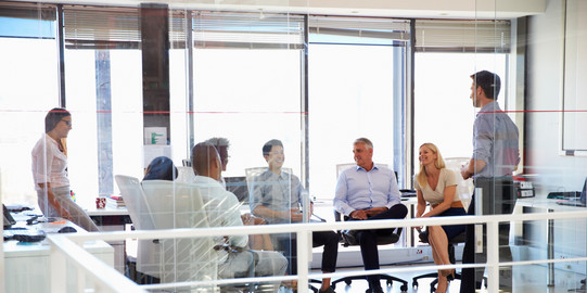 six people sitting together in a bright room are facing each other